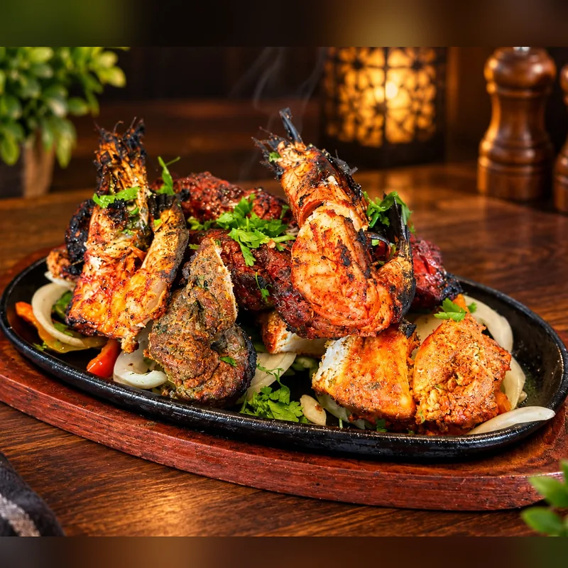 Tandoori Mixed Grill : gambas, agneau tikka, seekh kebab et poulet tandoori servis fumants sur leur plat en fonte
